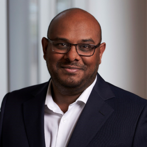 Biju Manthai is wearing a black blazer and white shirt
