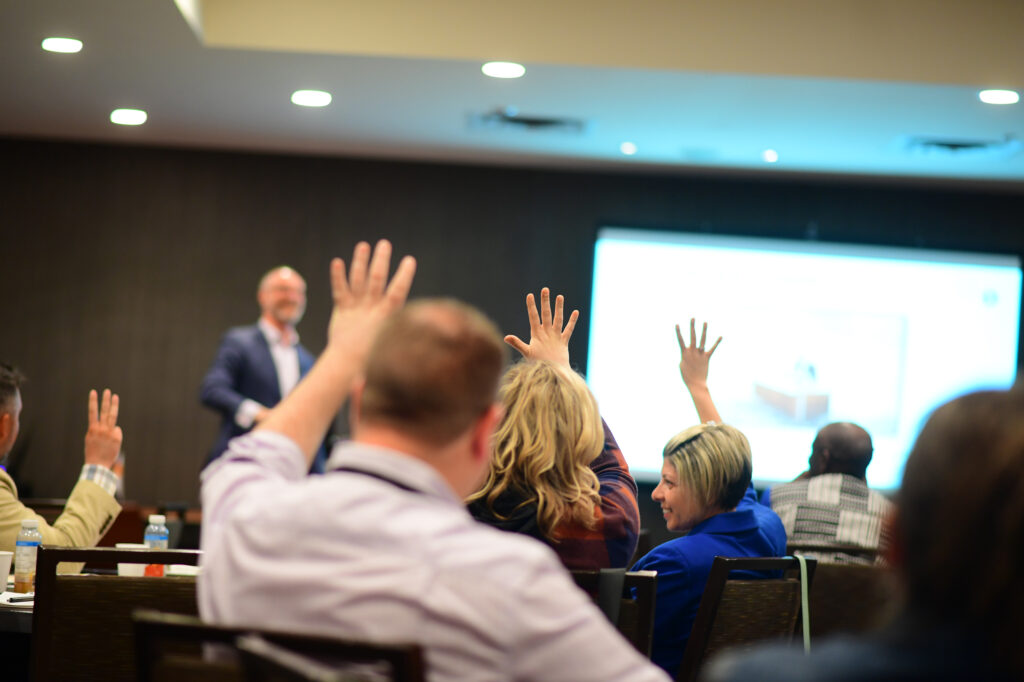 Audience members with raised hands in a classroom setting