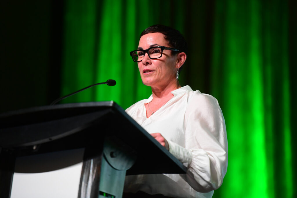 A woman speaking at a podium with green lighting
