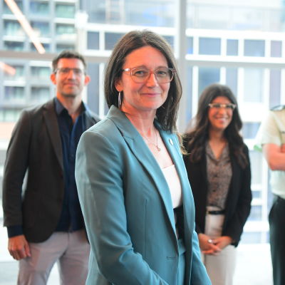 Portrait-style photo of a woman smiling, with others blurred in the background.